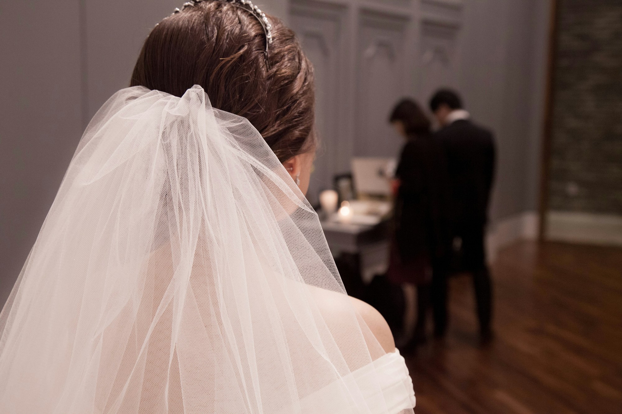Duvaklı gelinin arkasında, uzakta hazırlanan damat